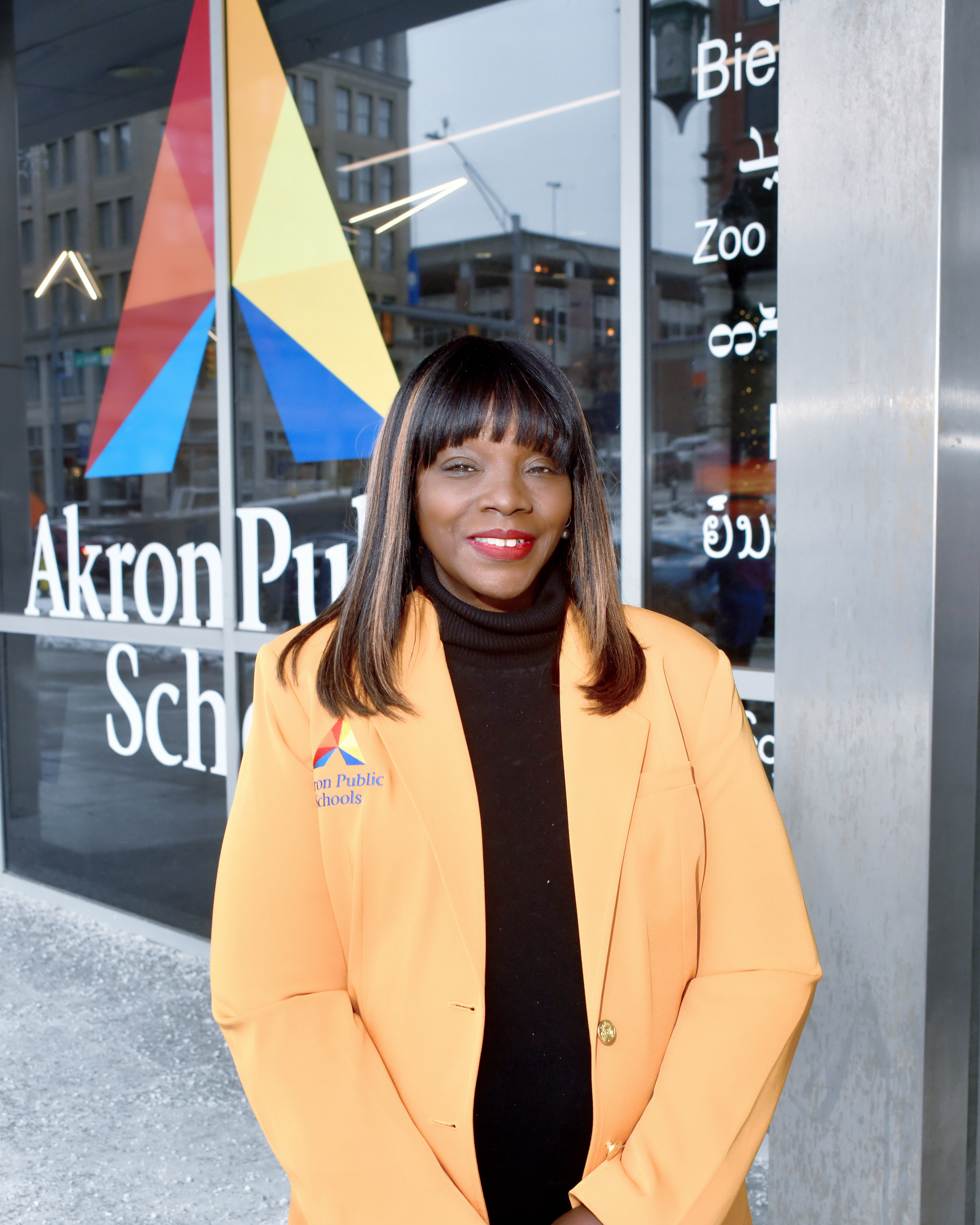 African-American woman wearing peach blazer and black turtle neck smiling