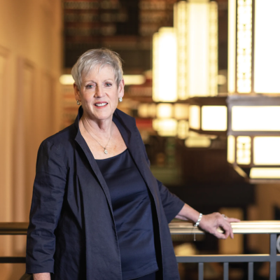 Woman with grey hair in a black suit posing by stairwell